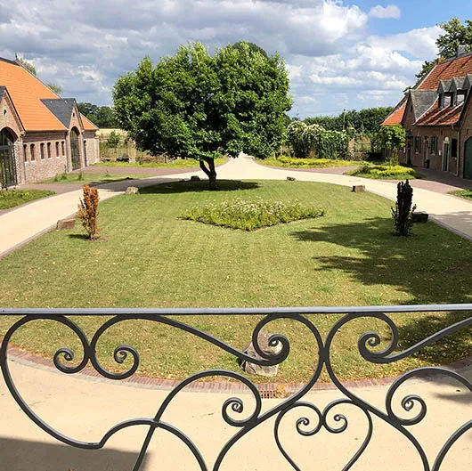 Angelegte Gartenanlage mit Rasenfläche, Beeten und schmiedeeisernem Zaun