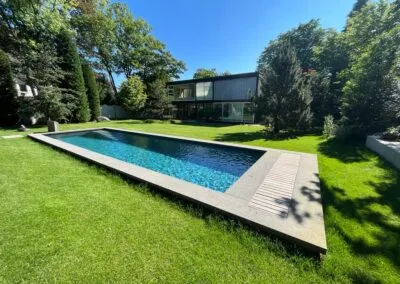Gartenanlage mit Pool, Natursteinmauer und Rasenfläche