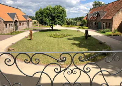 Gartenanlage mit Rasenfläche und Wegen an einem Hofgebäude