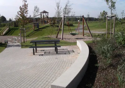 Spielbereich mit Sitzstufen aus Beton und Holzspielgeräten
