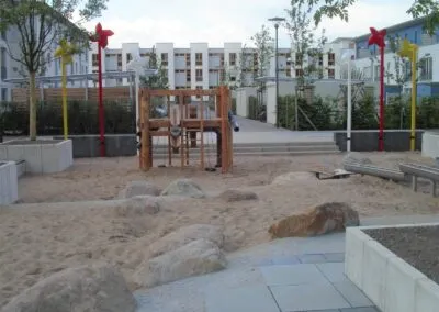 Sandspielbereich mit Holzspielgerät und Sitzbank