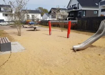 Spielplatz mit Rutsche und Sandfläche in einem Neubaugebiet