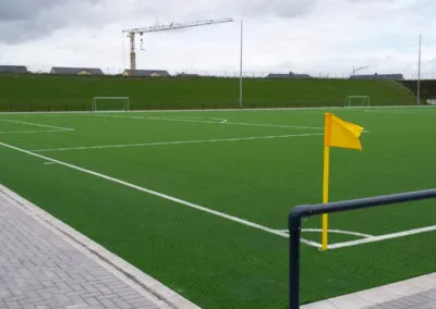 Sportplatz mit Kunstrasen und eingeschaltetem Flutlicht
