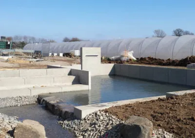 Angelegte Wasserstelle mit Natursteinstufen in einem neuen Wohnquartier